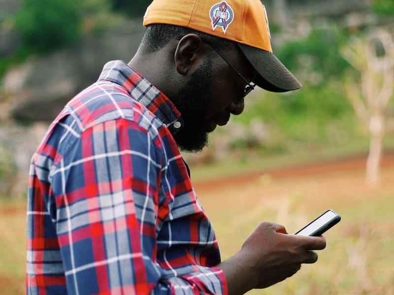 A field worker outdoors checking his phone.
