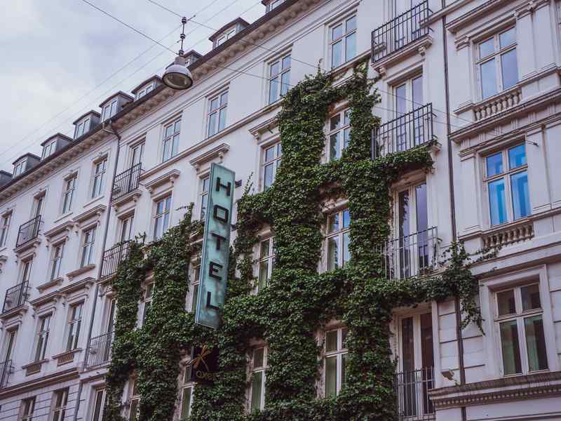 An ivy-covered hotel facade with a vertical hotel sign.