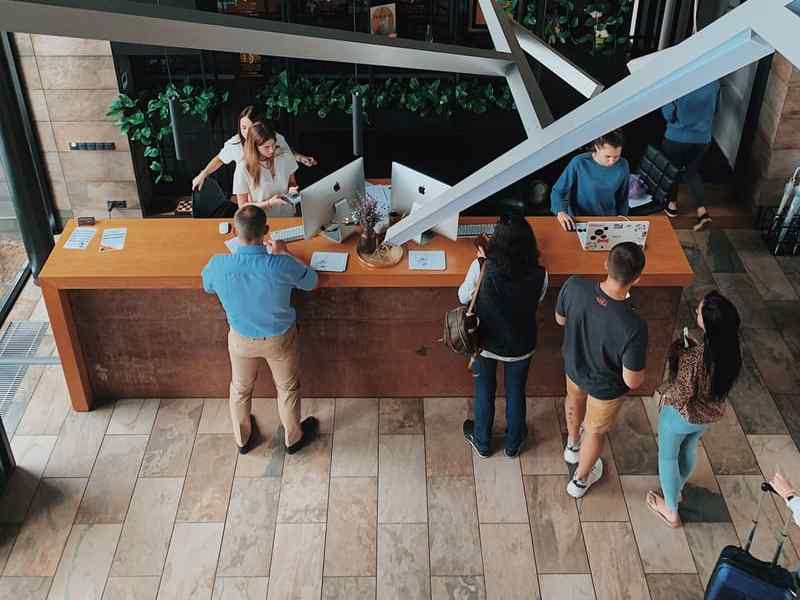 A busy hotel reception desk seen from above, with guests waiting.