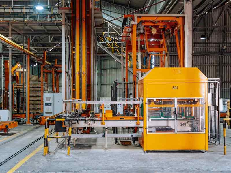A factory production line with conveyors and an enclosed machine.